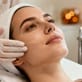 Esthetician applying a skincare serum to a client’s face during a professional facial treatment.