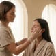 Esthetician gently applying skincare product to a client’s face in a calm, beige-toned spa environment.