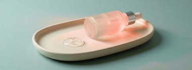 Minimal skincare serum bottle with dropper on a ceramic tray with gel texture sample on a soft blue background.