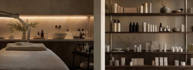 Esthetician gently applying skincare product to a client’s face in a calm, beige-toned spa environment.