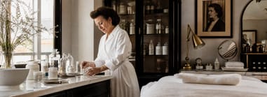 Esthetician hand-blending Christine Valmy skincare in an apothecary-style treatment room.